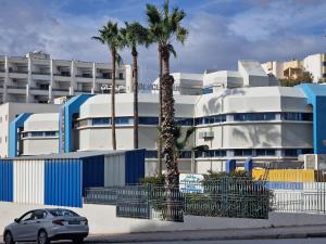 a car parked in front of a building with palm trees at Manar Clinique House in Tunis