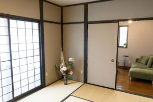 ein Wohnzimmer mit einer Tür und einer Vase aus Blumen in der Unterkunft 一棟貸 風kaze in Ōgaki