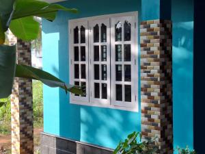 een raam aan de zijkant van een blauw huis bij Casa Tangerina in Varkala