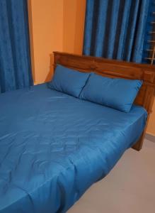 een bed met blauwe lakens en blauwe gordijnen bij Casa Tangerina in Varkala