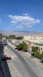 Qala View Inn في نزوى‎: شارع مدينة فارغ فيه مباني وسيارات على الطريق