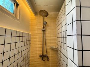 un bagno con doccia e piastrelle gialle e bianche. di Nana Best Hostel a Makkasan