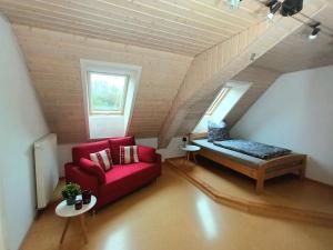 a living room with a red couch and a bed at Gästehaus am Hofberg in Thalmässing
