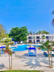 a resort pool with a table and palm trees at Protels La Plage Resort in Bwejuu