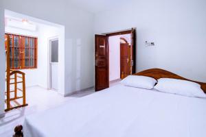 een witte slaapkamer met 2 bedden en een ladder bij Ramya Villa in Weligama +2 foto's