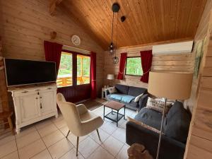 a living room with a couch and a tv at Chalets du Soleil in Mauroux