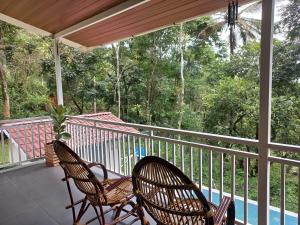 Dos sillas en un porche con vista a los árboles. en The Aradhya Villa, en Wayanad
