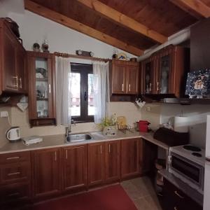 a kitchen with wooden cabinets and a sink and a window at Vrachni Stone House in Kalavrita +11 photos