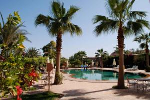una piscina con palme, tavoli e sedie di Hotel Dar Zitoune Taroudant a Taroudant