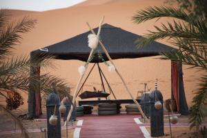 a tent in the middle of a desert with palm trees at Camel luxury camps Merzouga in Merdani