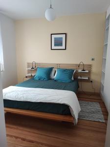 a bedroom with a large bed with blue pillows at Charme et authenticité pour 4 personnes 