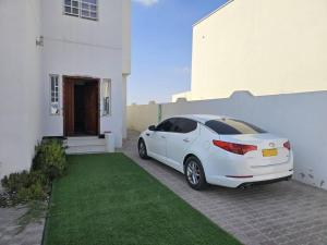 un coche blanco estacionado frente a una casa blanca en DrOmid, en Maţār as Sīb ad Duwalī