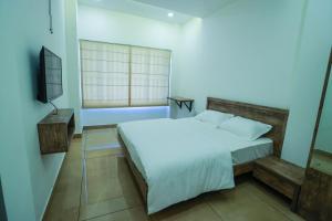 a bedroom with a white bed and a television at Atholi Residency in Mukkam