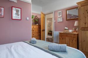 a bedroom with pink walls and a bed with towels on it at Heligog at Deanfield House Moelfre Sea view adult only appartment in Moelfre in Moelfre +25 photos