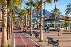 a street with palm trees and people walking down a sidewalk at Apartamentos La Jabega in Fuengirola