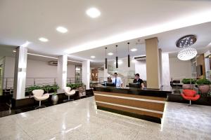 two people standing at a counter in a lobby at Hotel Metropolitan in Campo Grande
