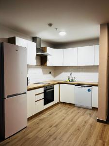 28th Floor Sky City View Apartment في إسكوبية: مطبخ مع الأجهزة البيضاء والأرضيات الخشبية