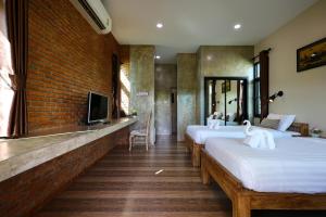 a row of beds in a room with a brick wall at Chiang Mai Garden Bungalows in Chiang Mai