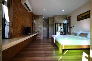 a bedroom with a bed and a tv on a brick wall at Chiang Mai Garden Bungalows in Chiang Mai