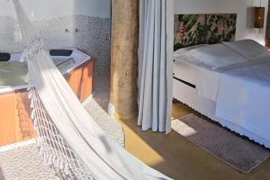 a hammock in a room with a bed and a tub at OPN Guest House Ilhabela in Ilhabela