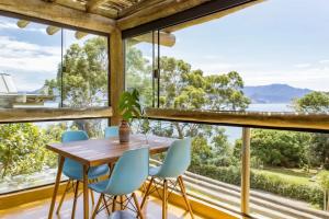 a dining room with a table and chairs and large windows at OPN Guest House Ilhabela in Ilhabela