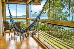 a hammock in a room with windows at OPN Guest House Ilhabela in Ilhabela