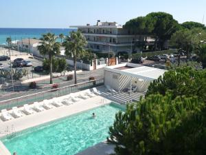 a swimming pool with chairs and a building and the ocean at Résidence Goélia Royal Cap in Villeneuve-Loubet