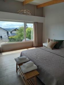 a bedroom with a large bed and a large window at Abra Dina Huapi in Dina Huapi