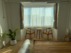 チェンマイにあるCloud Houseのテーブルと椅子と窓のあるリビングルーム