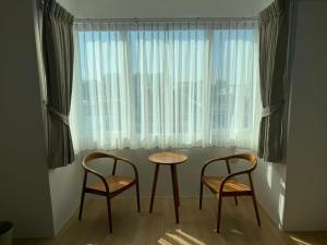 チェンマイにあるCloud Houseの窓の前にテーブルと椅子2脚