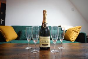 a bottle of wine sitting on a table with four wine glasses at L'appartement de la fontaine in Mutzig