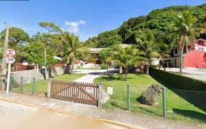 a fence in front of a park with palm trees at Lorena'Haus in Bombinhas