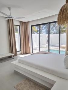 a white bedroom with a large bed and large windows at Amour Beach Villas in Paje +49 photos