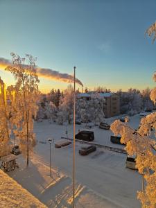a parking lot with snow covered trees and a building at Tievastreet Harmony Apartment in Rovaniemi