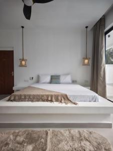 een slaapkamer met een groot wit bed en 2 verlichting bij Amour Beach Villas in Paje