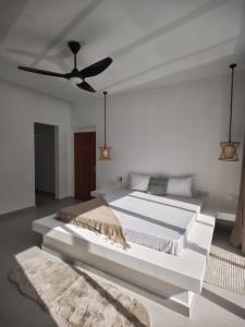 een witte slaapkamer met een groot wit bed en een plafond bij Amour Beach Villas in Paje