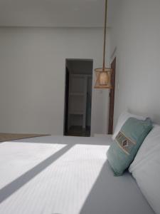 een wit bed met een groen kussen erop bij Amour Beach Villas in Paje