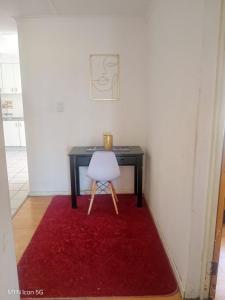 a desk with a white chair and a red rug at Quigney House on 66 Rhodes in East London