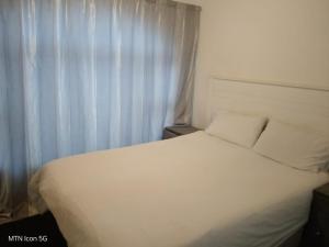a white bed in a room with a window at Quigney House on 66 Rhodes in East London