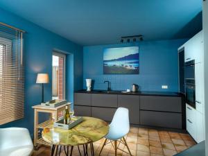 a kitchen with blue walls and a table and chairs at Stylish Apartment Zander On The Eider River Bend in Süderstapel
