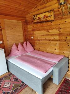 a bed in a wooden cabin with pink pillows at Harrys Blockhütte in Karres