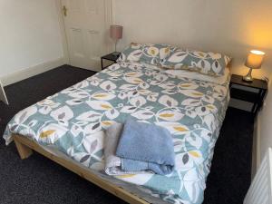 a bed with a blanket and pillows on it at Lovely Central Belfast 4 Bedroom Period Home in Belfast