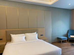 Hotel P4 City Center Jabalpur في جبلبور: غرفة نوم بها سرير كبير وكرسي أزرق