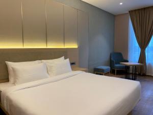 Hotel P4 City Center Jabalpur في جبلبور: غرفة نوم بها سرير أبيض وكرسي أزرق