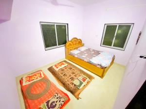 a small bedroom with two beds and two windows at Shri Laxmi Villa in Akalkot