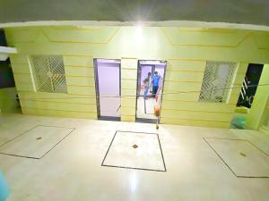 a room with a yellow wall with two people in the doorway at Shri Laxmi Villa in Akalkot