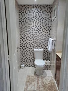 a bathroom with a toilet and a tiled wall at Haytam in Sale +3 photos
