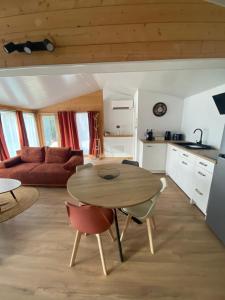 a kitchen and living room with a table and chairs at Chalet bois cosy indépendant Saint Jean de Niost in Saint-Jean-de Niost