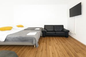 a bedroom with a bed and a leather couch at Old Town Apartments in Düsseldorf