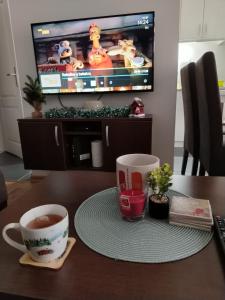 a table with two cups of coffee and a tv at ROSA in Vrnjačka Banja +27 photos